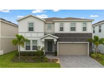 Charming two-story home with a stone accent, a gray-tone garage door and a landscaped front yard with palm trees at 4321 Lana Avenue, Davenport, FL 33897