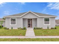 Charming single-story home with a modern front facade, well-manicured lawn, and a stylish wood-look front door at 4955 Castle E St, Kissimmee, FL 34758