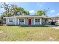 Charming one-story home featuring a brick facade, a bright red front door, and a covered carport at 5210 Grandview Dr, Orlando, FL 32808