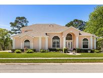 Charming single-story home featuring a manicured lawn, arched windows, and a light peach exterior at 6651 Sylvan Woods Dr, Sanford, FL 32771