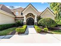 Stately home exterior featuring a grand arched entrance, manicured landscaping, and a tile roof at 257 New Gate Loop, Lake Mary, FL 32746