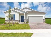 Charming single-story home with brick driveway, blue door, and manicured lawn under a partly cloudy sky at 4113 Jespersen St, Apopka, FL 32712