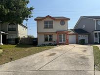 Two-story house with a long concrete driveway, neutral paint with terra cotta trim and an attached garage at 7834 Brockwood Cir # 2, Orlando, FL 32822