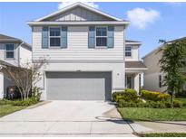 Charming two-story home featuring light gray siding, blue shutters, a two-car garage, and well-maintained landscaping at 17394 Million Lakes Ct, Clermont, FL 34714