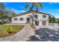 Two-story home featuring a paver driveway, mature palm tree, and neutral color palette at 40140 Swift Rd, Eustis, FL 32736