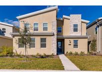 Modern two-story home with tan siding and stone accents, complemented by a well-manicured lawn and inviting landscaping at 2859 Bookmark Dr, Kissimmee, FL 34746