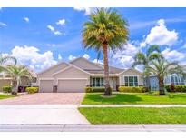 Charming single-story home with a three-car garage, manicured lawn and tropical landscaping including mature palm trees at 4770 Cypress Forest Ln, St Cloud, FL 34772