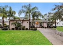 Stunning single-story home featuring a well-manicured lawn, mature palm trees, and a welcoming double door entrance at 5543 Grey Hawk Ln, Lakeland, FL 33810