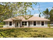 Charming single-story home featuring a light gray exterior, white trim, tile roof, and well-maintained lawn at 7847 Golf Paradise Way, Clermont, FL 34711