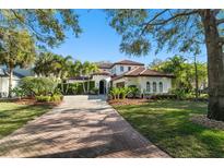 Stunning single-Gathering home boasts lush landscaping, a red tile roof, and a brick-paved driveway at 9783 Covent Garden Dr, Orlando, FL 32827