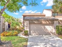 Exterior view of home featuring an attached two-car garage, walkway, and lovely tropical landscaping at 1105 Woodbine St, Fern Park, FL 32730