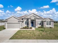 Charming single-story home featuring stone accents, a well-manicured lawn, and a two-car garage at 1113 Caloosa Ridge Way, Babson Park, FL 33827