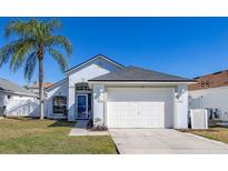 Charming single-story home with a well-manicured lawn, mature palm tree, and attached two-car garage in a serene neighborhood at 121 Sonja Cir, Davenport, FL 33897