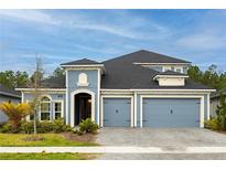 Charming two-story home features a blue exterior, paved driveway, and a three-car garage at 345 Aquamarine Way, Daytona Beach, FL 32124