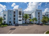 Contemporary building with parking, manicured greenery, balconies, and blue and white accents at 4751 Clock Tower Dr # 203, Kissimmee, FL 34746