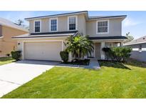 Charming two-story home featuring a well-manicured lawn and an attached two-car garage at 608 Abaco Ct, Kissimmee, FL 34746