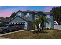 Charming two-story home with an attached garage, well-manicured lawn and tasteful landscaping with tropical plants at 2204 Hammock Moss Dr, Orlando, FL 32820