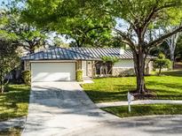 Charming single-story home with manicured lawn, stone accents, gray metal roof, and a two-car garage at 2952 Ashwood Ct, Apopka, FL 32703