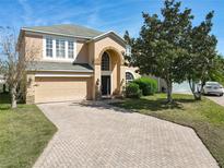 Inviting two-story home featuring a brick driveway, attached two-car garage, and an arched entryway at 643 Willett Dr E, Winter Garden, FL 34787