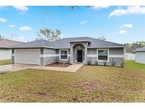 Charming single-story home showcasing a two-car garage, arched front entrance, and a well-maintained lawn at 205 Lori Ct, Umatilla, FL 32784