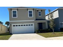 Two-story home featuring a spacious two-car garage, manicured lawn, and modern architectural design at 2597 Shamrock St, Tavares, FL 32778