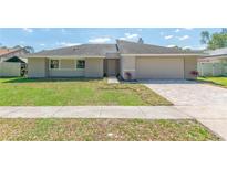 Charming single-story home with a manicured lawn and a paved driveway leading to an attached two-car garage at 323 Shadow Oak Dr, Casselberry, FL 32707