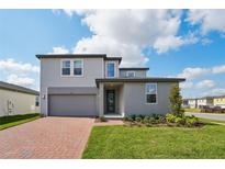 Two-story home with a brick driveway, lawn, and a mix of siding and stucco exterior at 4556 Windy Oak Way, St Cloud, FL 34772
