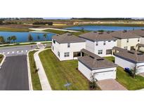 New two-story homes with attached garages and well-manicured lawns overlook a tranquil lake at 5059 Lake Hamlin Trl, Winter Garden, FL 34787