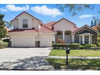 Charming two-story home featuring a red tile roof, three-car garage and manicured front yard with stone accents at 9042 Heritage Bay Cir, Orlando, FL 32836