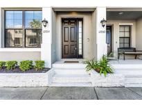 Charming front entrance with a stylish black door, complemented by lush greenery and inviting lighting at 12934 Cats Claw Ln, Orlando, FL 32828