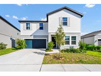 Charming two-story home with a blue garage door, landscaped yard, and a combination of white and gray siding at 2126 Derwent Dr, Davenport, FL 33896
