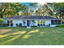 Charming one-story home featuring a well-maintained lawn, mature trees, and a welcoming entrance with a blue door at 31024 Prestwick Ave, Sorrento, FL 32776