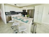 Bright kitchen features white cabinetry, stainless appliances, an island, and barstool seating at 3121 Paradox Cir # 307, Kissimmee, FL 34746