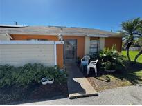 Orange townhome with a sidewalk leading up to the front door with lush greenery and lawn at 46 Silver Park Cir, Kissimmee, FL 34743