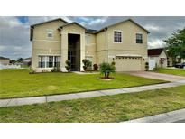 Well-maintained two-story home with a two-car garage, manicured lawn, and front garden at 5453 Crepe Myrtle Cir, Kissimmee, FL 34758