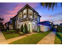 Stunning two story exterior with balcony, manicured landscaping and a beautiful sunset sky above the residence at 8872 Bismarck Palm Dr, Winter Garden, FL 34787
