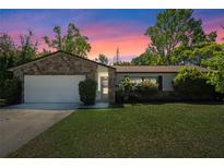 Charming single-story home featuring a stone accent wall and well-maintained lawn at sunset at 412 Short Dr, Poinciana, FL 34759