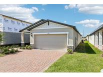 Charming single-story home features a brick driveway, light-colored exterior, and a two-car garage on a sunny day at 4973 Kaia Ave, Winter Haven, FL 33884