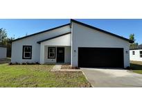Modern single-story home featuring a black two-car garage, minimalist landscaping, and bright white stucco exterior at 168 Marion Oaks Ln, Ocala, FL 34473