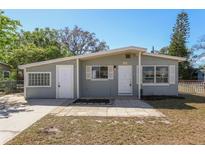 Charming single-story home with a light grey exterior, complemented by white trim, shutters, and a well-maintained front yard at 2318 Vincent Rd, Orlando, FL 32817