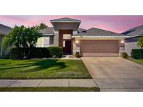 Inviting single-Gathering home featuring a well-manicured lawn, mature landscaping, and an attached two-car garage at 2519 Cypress Trace Cir, Orlando, FL 32825