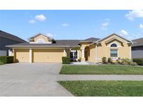 Charming yellow home with a well-manicured lawn and a three-car garage at 419 Coventry Rd, Davenport, FL 33897