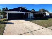 Charming single-story home featuring a black garage door, a well-maintained lawn, and an inviting front entrance at 6130 Gamble Dr, Orlando, FL 32808