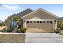 Charming single-Gathering home featuring a beige exterior, two-car garage, and well-maintained landscaping at 459 Tivoli Cir, Davenport, FL 33837