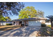 Charming single-story home featuring a two-car garage, manicured lawn and mature trees at 613 Andrew St, Altamonte Springs, FL 32714