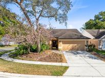 Charming single-story home featuring a manicured lawn, blooming tree, and a two-car garage at 134 Woodleaf Dr, Winter Springs, FL 32708