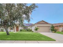 Charming single-story home boasts a lush lawn, two-car garage, and decorative tree and solar panels at 14815 Tullamore Loop, Winter Garden, FL 34787