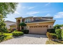 Charming two-story home featuring a brick driveway, a two-car garage, and beautifully landscaped front yard at 221 Calliope St, Ocoee, FL 34761