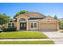 Charming single-story home featuring a well-manicured lawn, double door entry and an attached two-car garage at 813 Havenwood Dr, Orlando, FL 32828