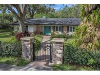 Charming single-story brick home with a manicured lawn, stone pillars, and beautiful turquoise double front doors at 137 Tangerine Ave, Oviedo, FL 32765